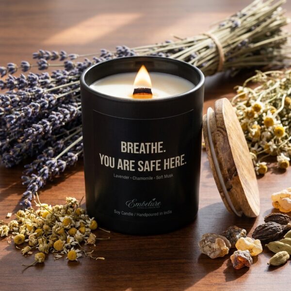 Premium raw ingredients including dried lavender buds and chamomile flowers spread around a black candle jar