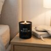 A peaceful bedroom nightstand setup featuring a lit lavender and chamomile scented candle next to a book.